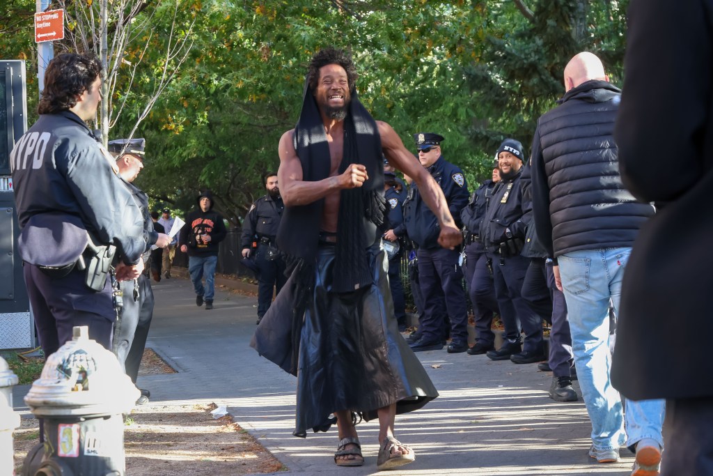 A homeless person passes in front of NYPD police officers in Washington Square Park.