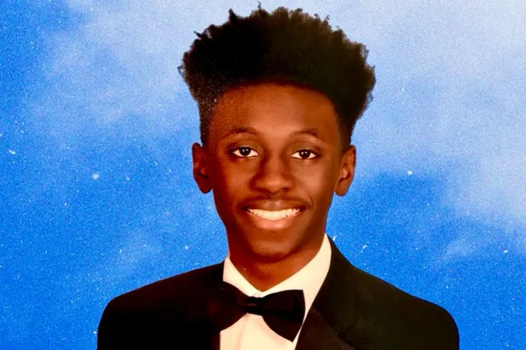 Donovan Metayer, a Parkland shooting survivor, smiling in a black suit and bow tie against a blue background.