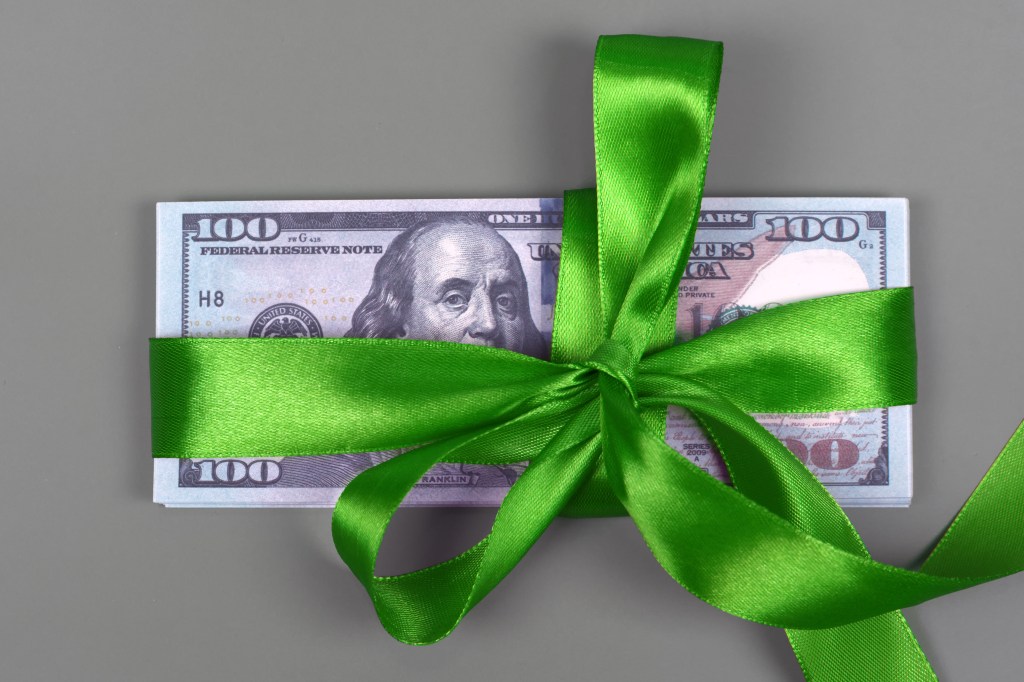 Stack of hundred dollar bills tied with a green ribbon bow.