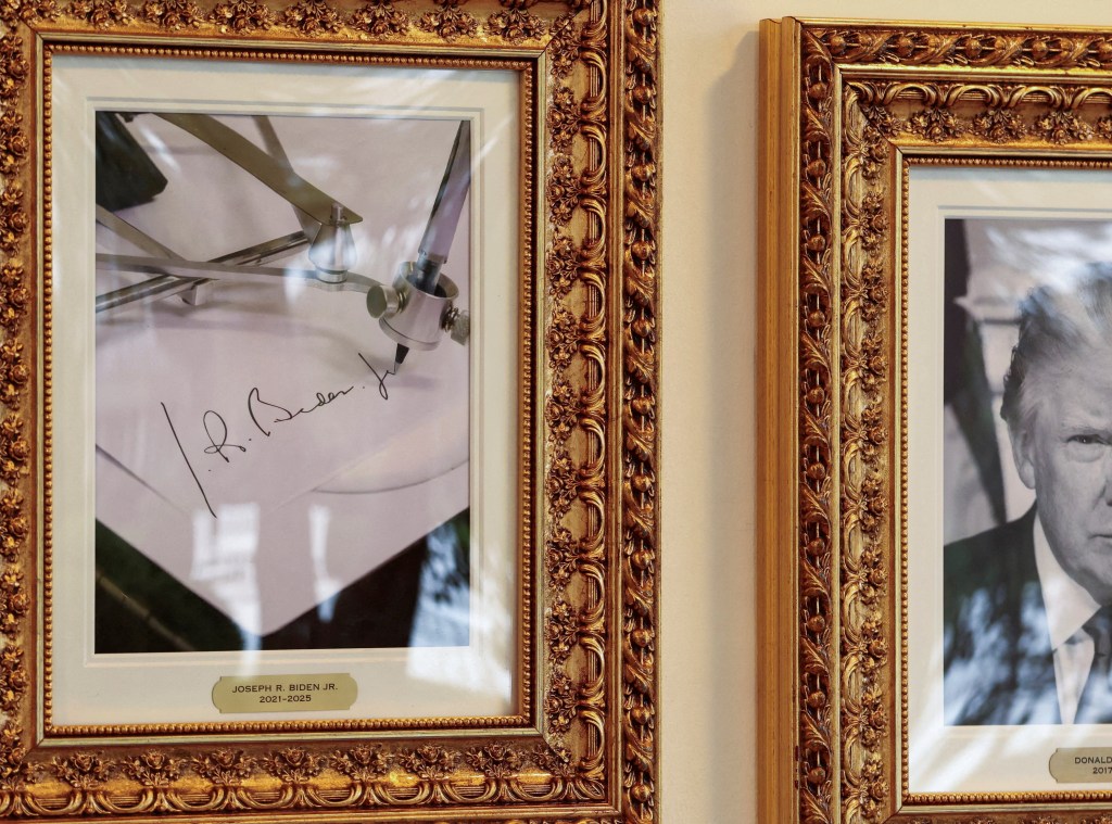 A framed autopen image of Joe Biden's signature, next to a framed black and white portrait of Donald Trump.