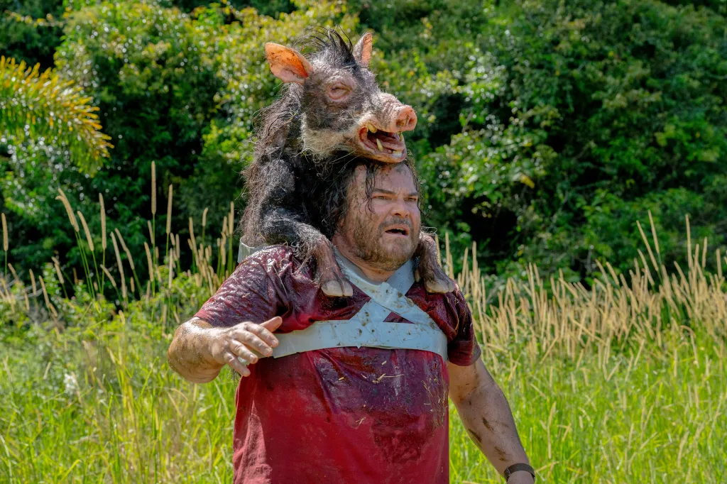 Jack Black wearing a boar on his back, covered in mud.