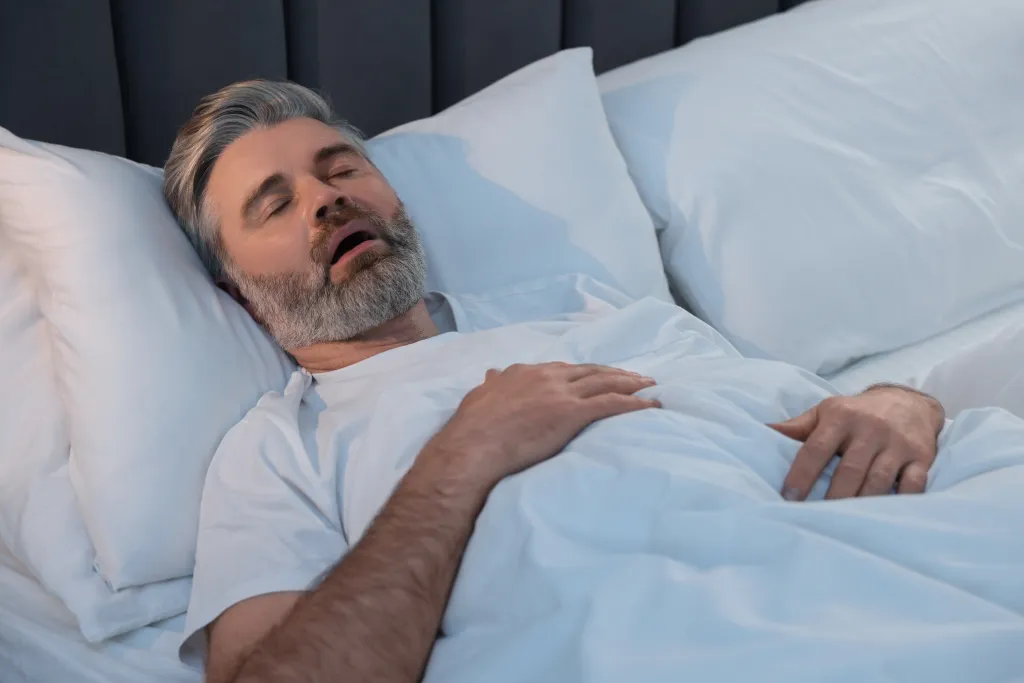 Man sleeping in bed with his mouth open.