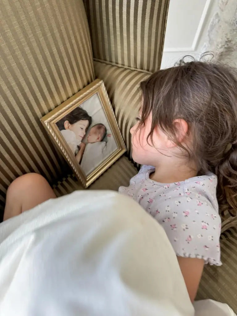Molly Carlton looking at a framed photograph of a child next to a baby.