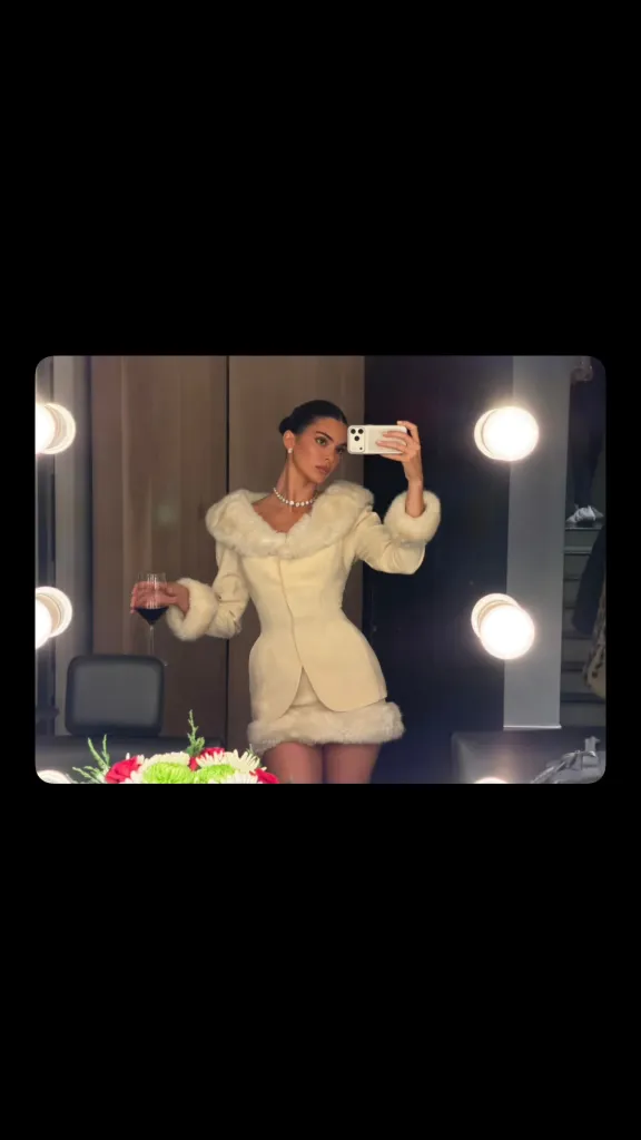 Kendall Jenner taking a mirror selfie while holding a glass of wine.