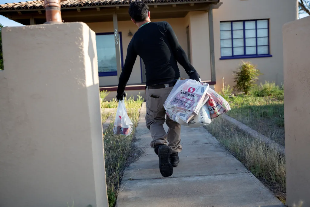 Instacart employee Eric Cohn wearing a respirator mask, carrying Safeway grocery bags.