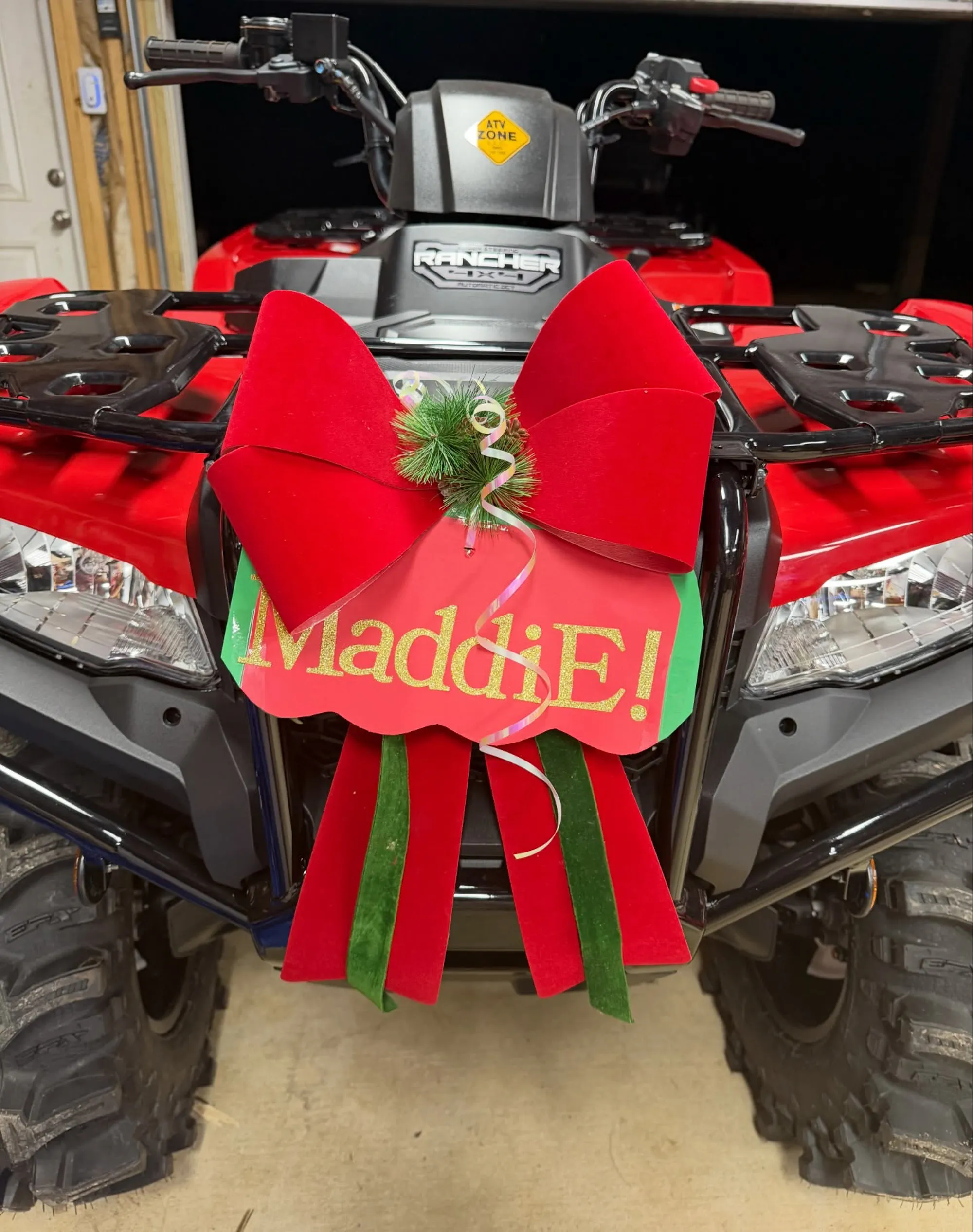 Close-up of the front of a red ATV decorated with a big red bow and a sign that reads 