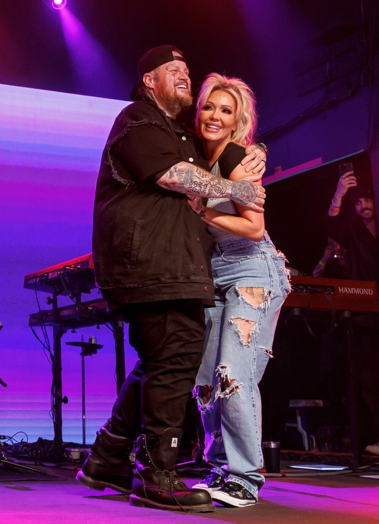 Jelly Roll and Bunnie Xo embracing on stage during a concert.