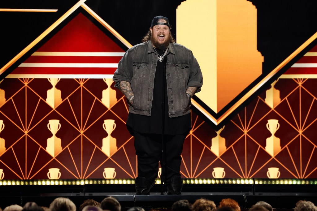 Jelly Roll on stage with Calder Cup trophy images in the background.
