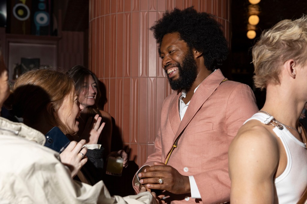 Jeremy O. Harris smiling and talking to people at the Erupcja premiere party.