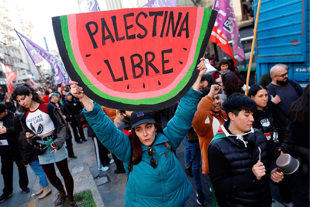 A woman holding a watermelon-shaped sign that reads