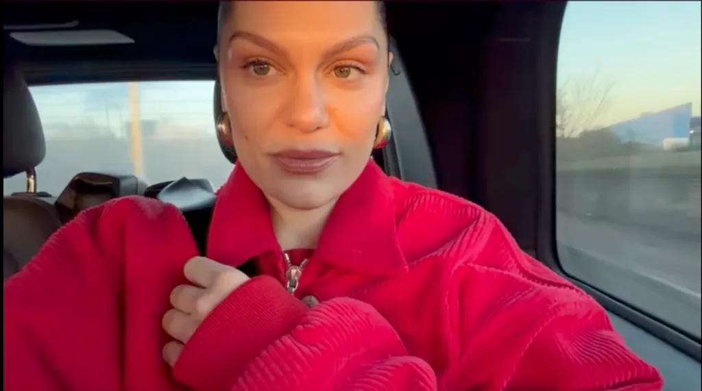 Jessie J wearing a red top with gold hoop earrings.