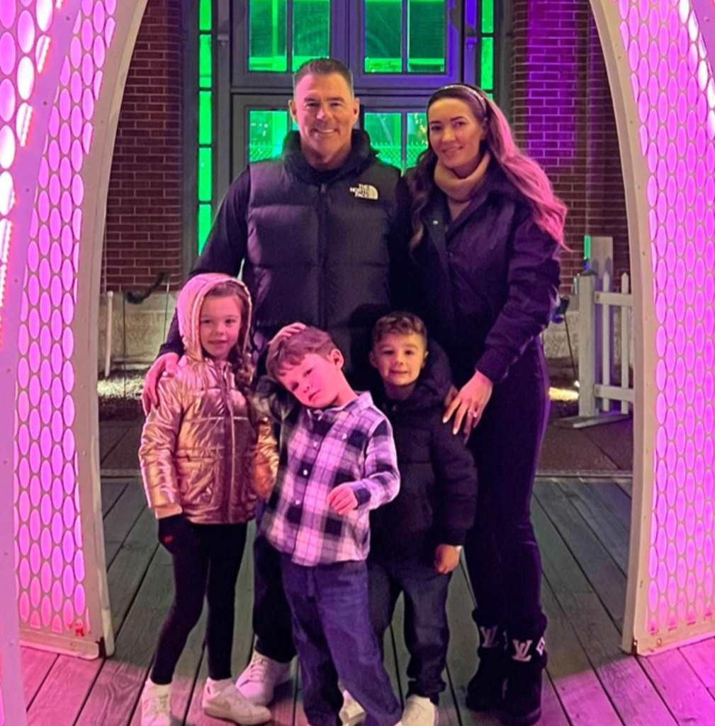 Jim Edmonds posing with his family, including his wife Kortnie and three children, under neon pink and green lights.