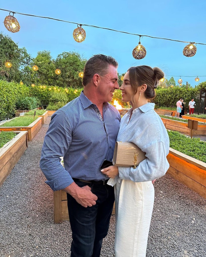 Jim Edmonds and a woman gazing at each other in a garden with string lights.