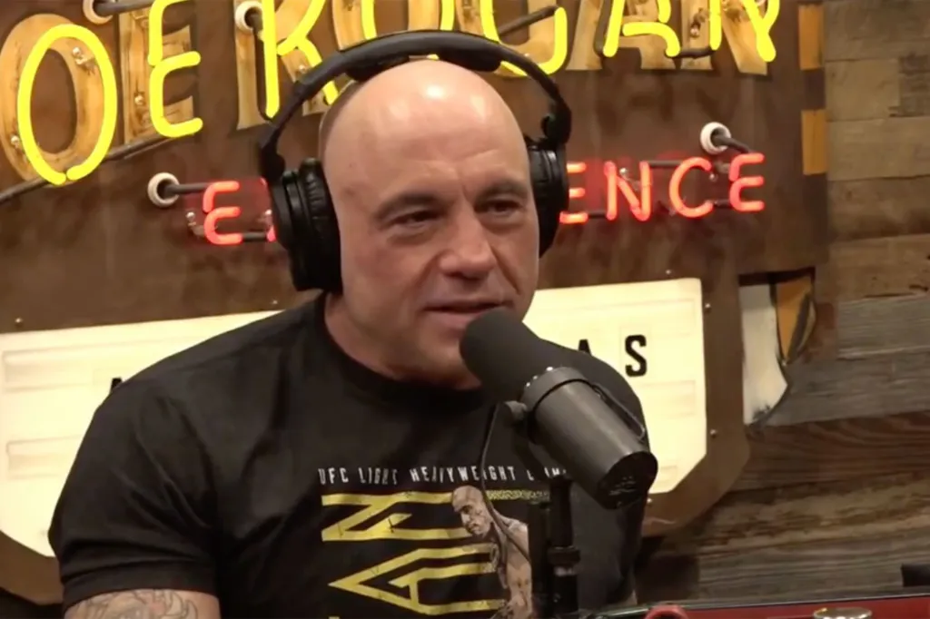 Joe Rogan speaking into a microphone with headphones on.