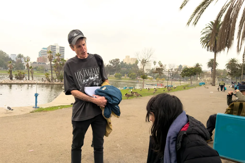 John Alle talks with a homeless woman at MacArthur Park in Los Angeles.