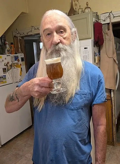 John Drake, 77-year-old gunman, holding a glass of frothy drink.