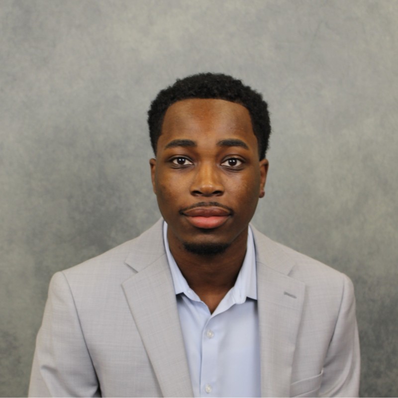 Joseph Oduro in a light blue shirt and light gray suit jacket.