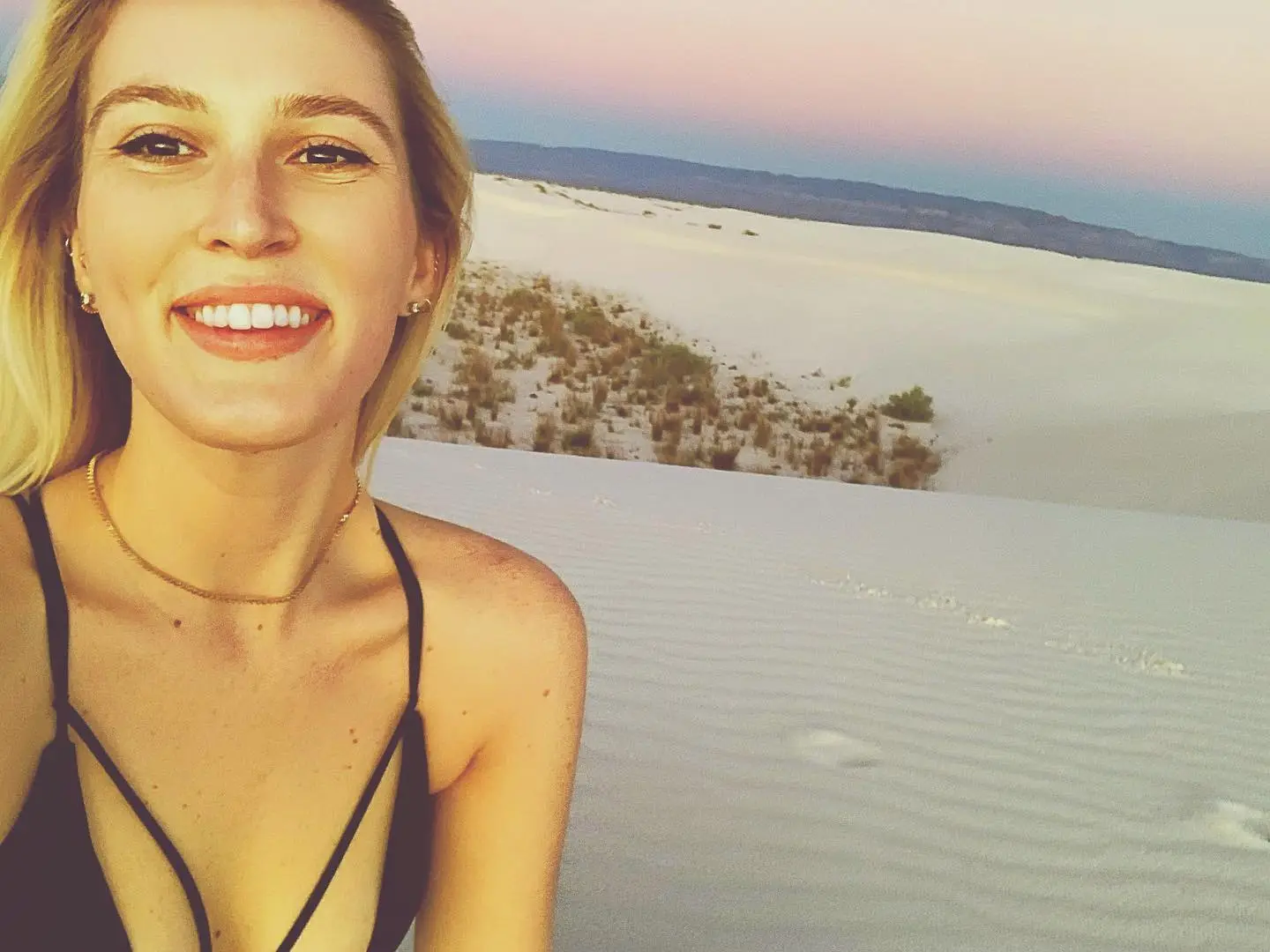 Journalist Olivia Nuzzi smiling in front of a white sand dune landscape.