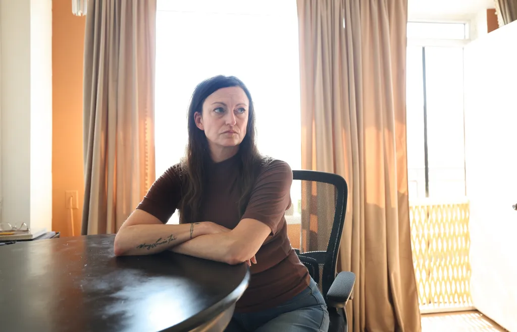 Claire Brosseau, who has applied for MAID, sitting at a table with her arms crossed.