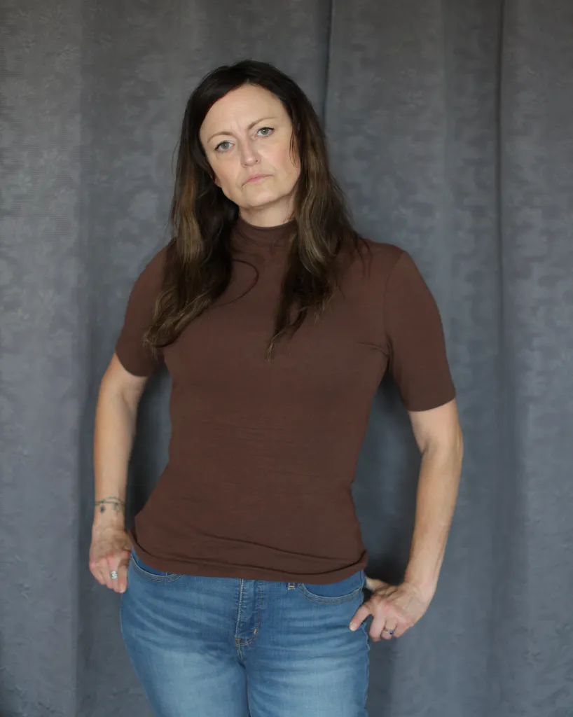 Claire Brosseau, who has applied for MAID, stands in her home with hands on her hips.