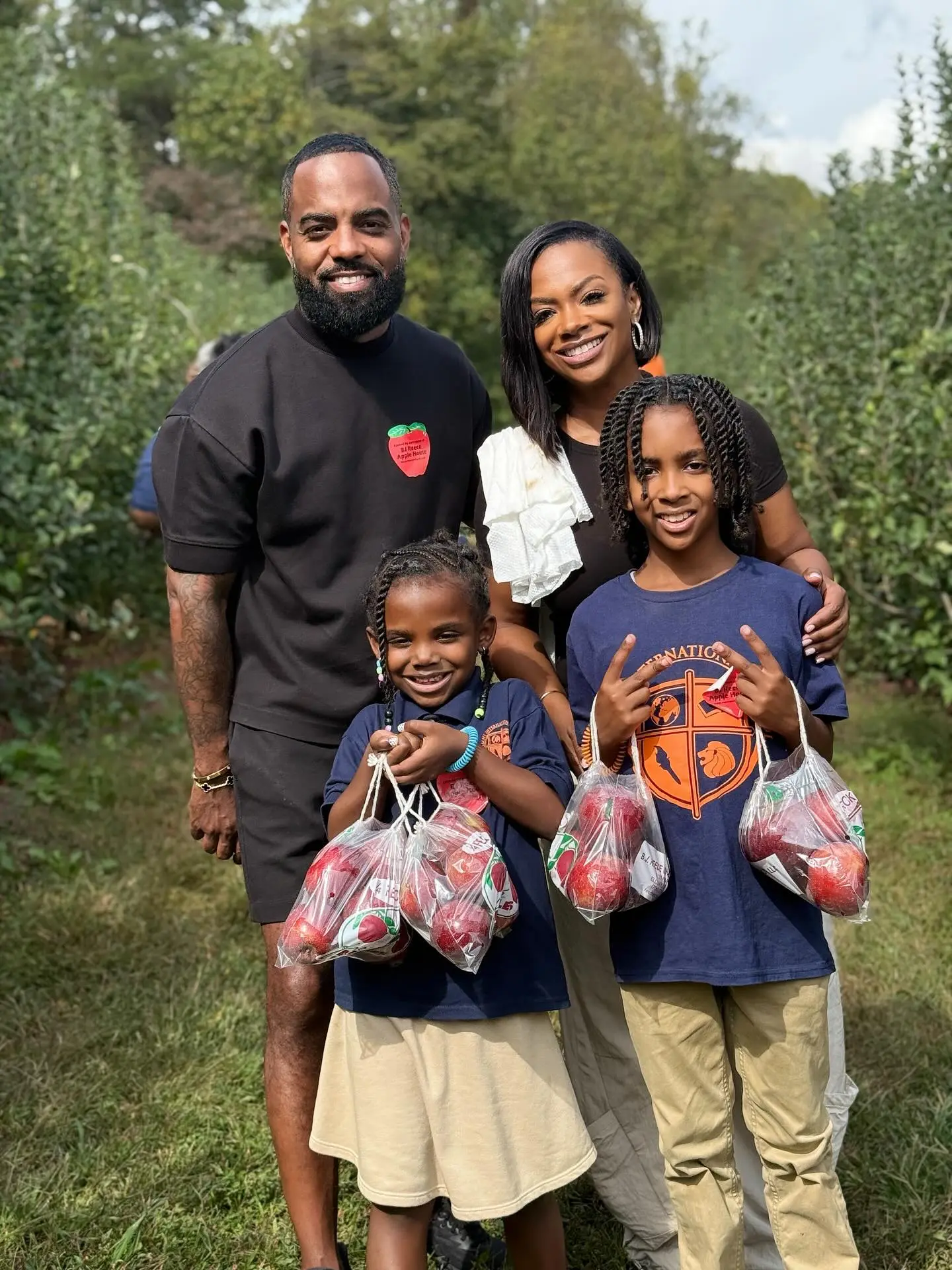 Kandi Burruss and Todd Tucker with their two children holding bags of apples.