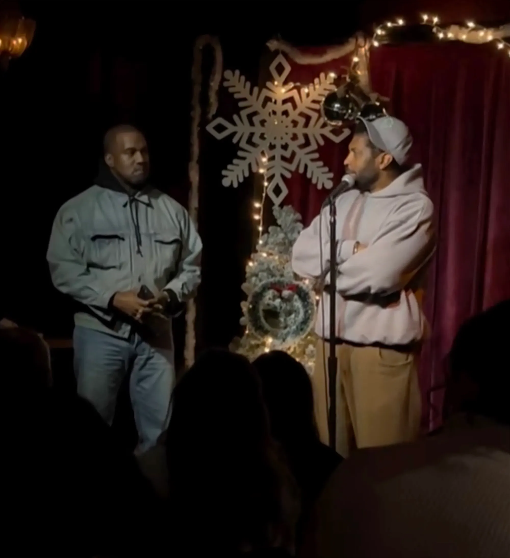 Kanye West brought on stage during Deon Cole's improv show, standing next to Cole, who is at a microphone.