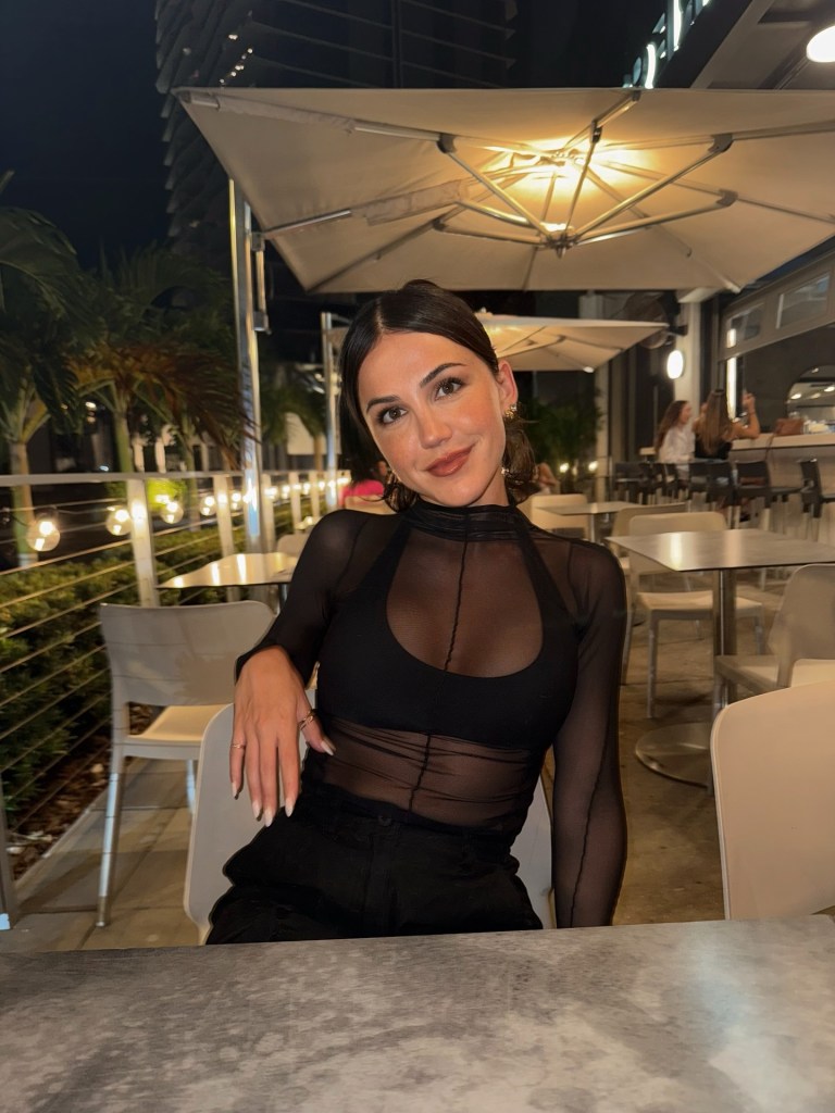 Kat Stickler smiling at a restaurant table.