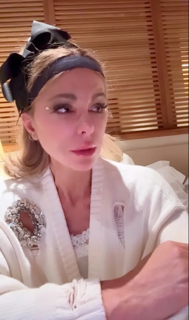 Kate Beckinsale wearing a black bow in her hair and a distressed white cardigan with a large brooch.