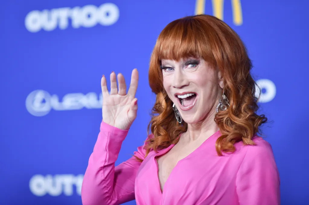 Kathy Griffin in a pink top waves at the Out100 celebration.