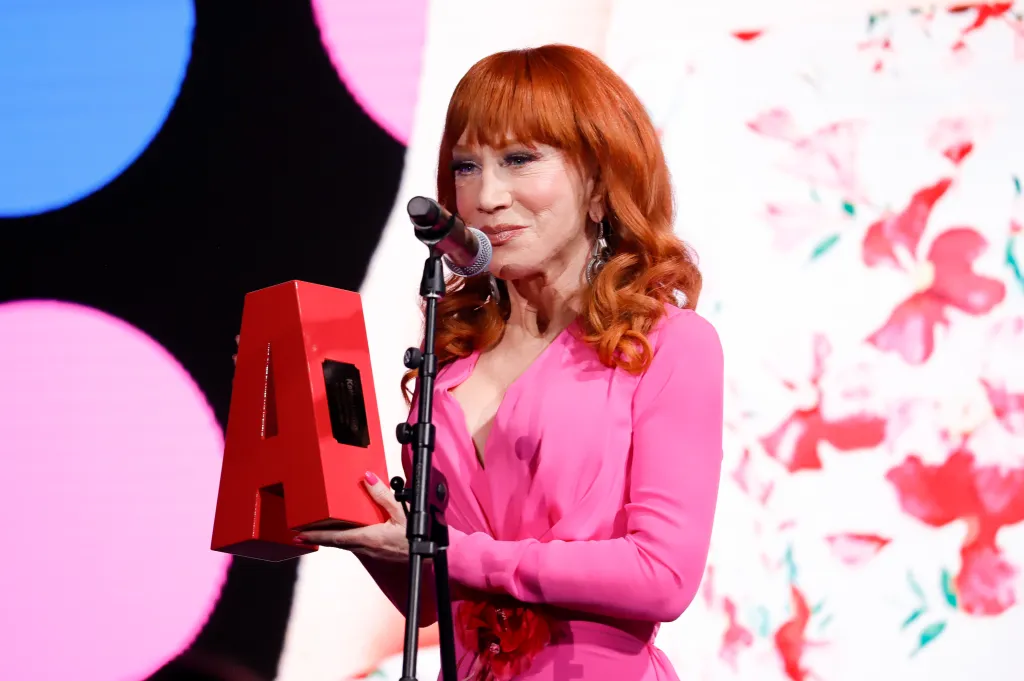 Kathy Griffin holding a red award with the letter 