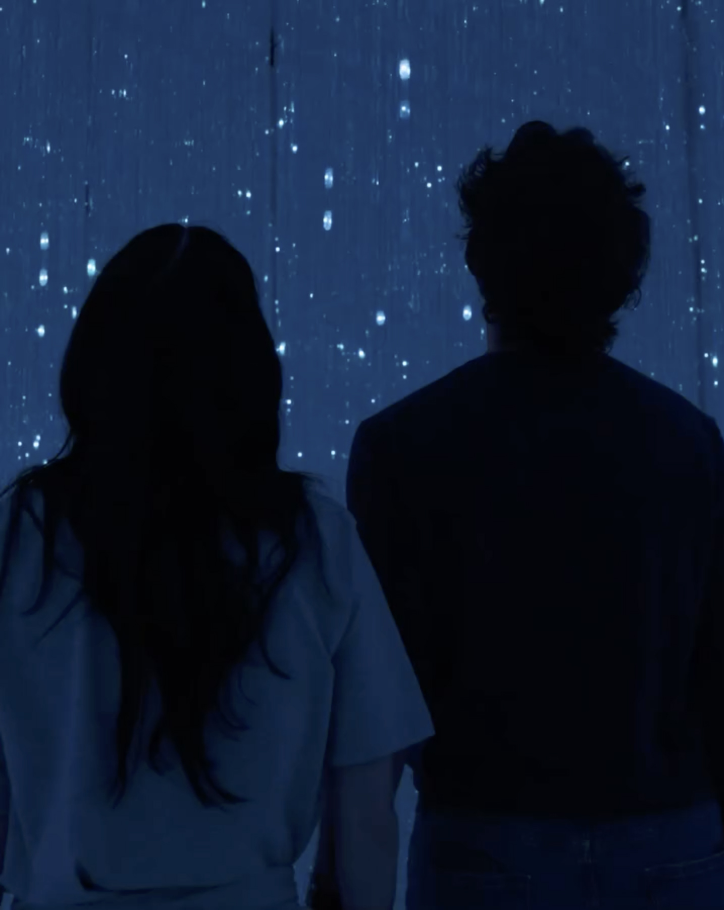 Katy Perry and Justin Trudeau watching an illuminated art exhibit.