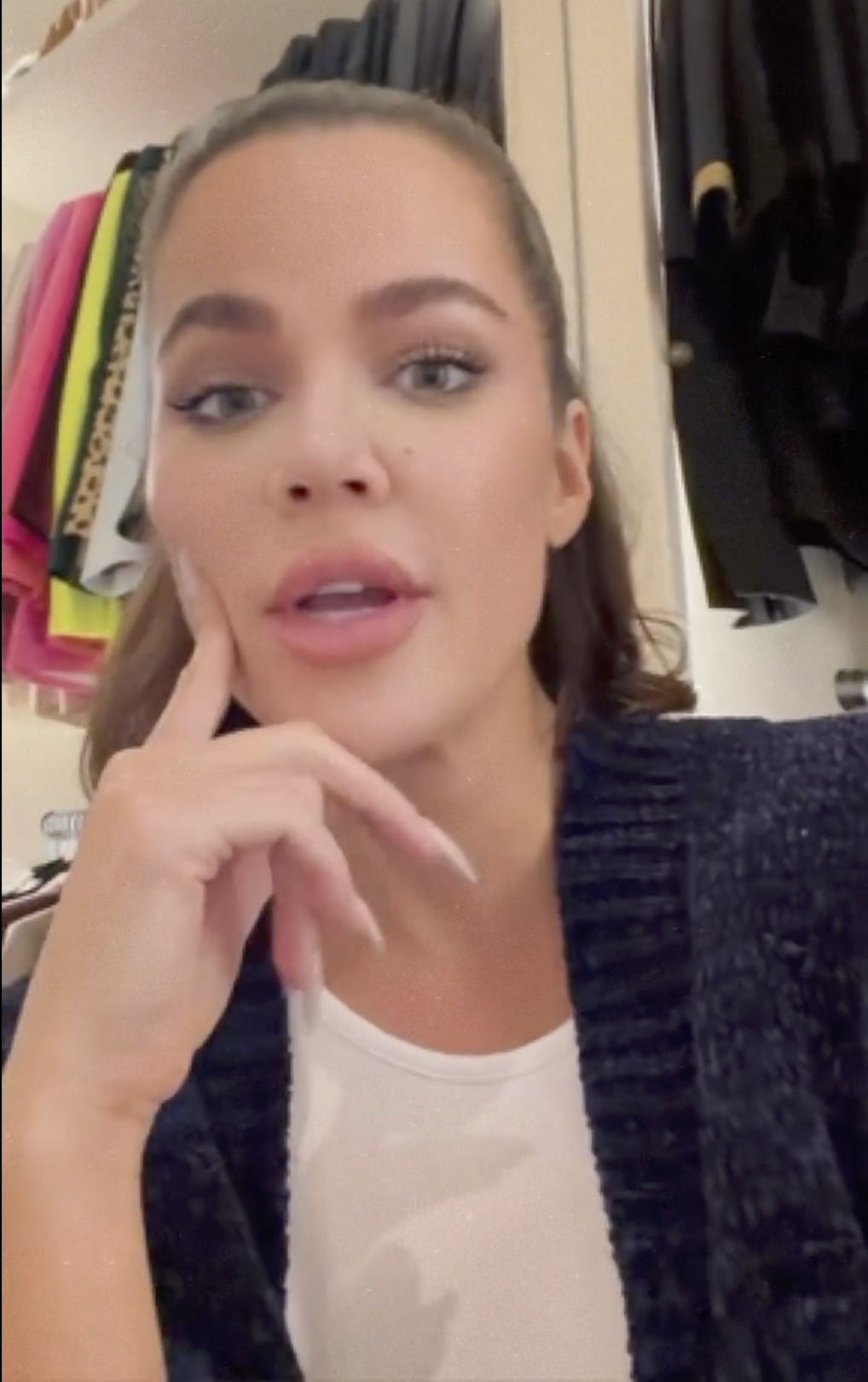 Khloé Kardashian talking, with her hand resting on her chin.