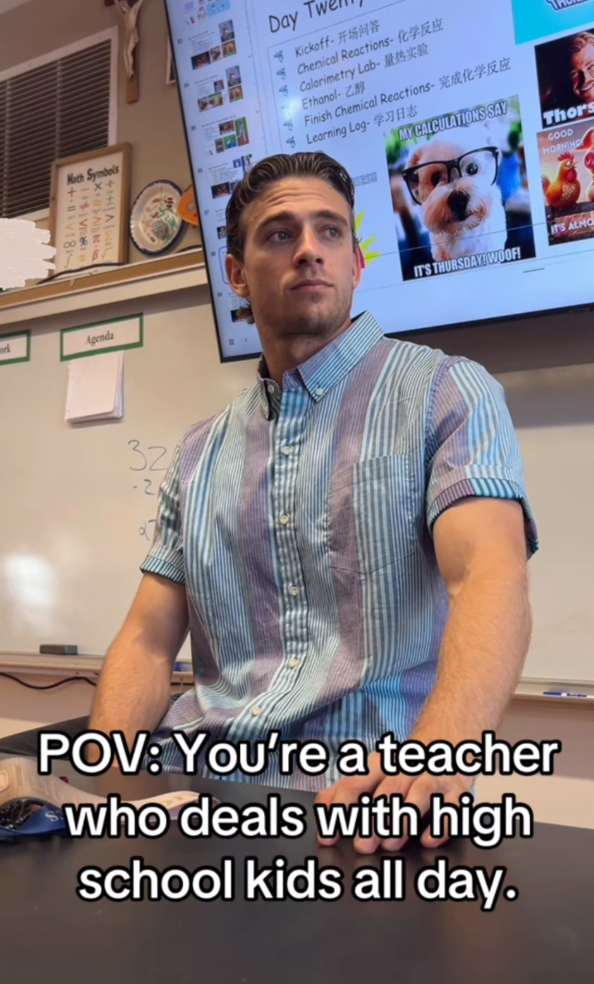 A male teacher in a striped shirt sitting at his desk.