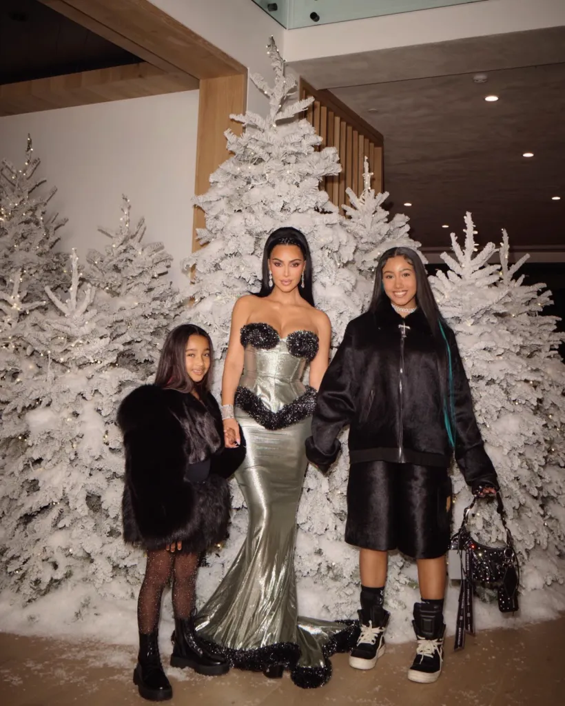 Kim Kardashian with her daughters North West and Chicago West in front of frosted Christmas trees.