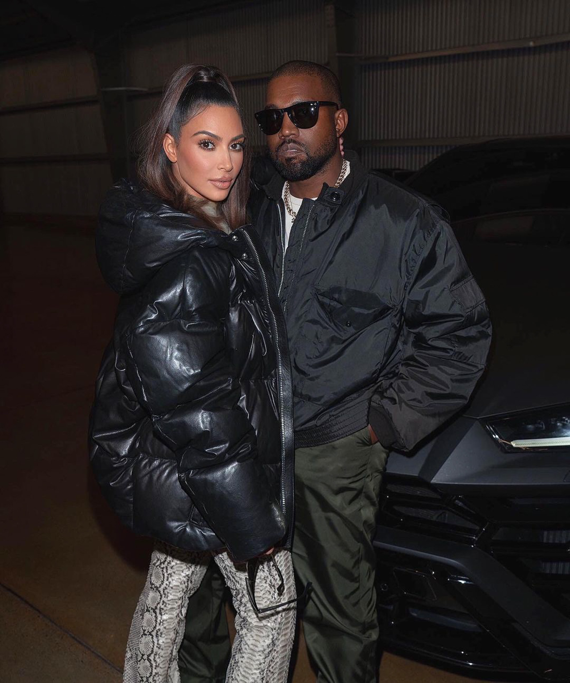 Kim Kardashian and Kanye West posing next to a car.