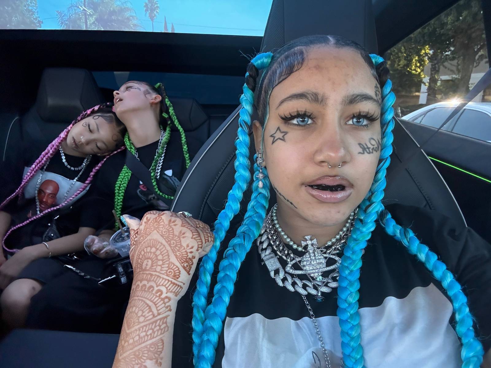North West wearing fake face tattoos, piercings, and blue braids.