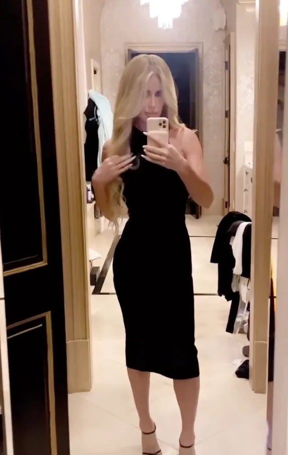 Kim Zolciak taking a mirror selfie in a black dress.