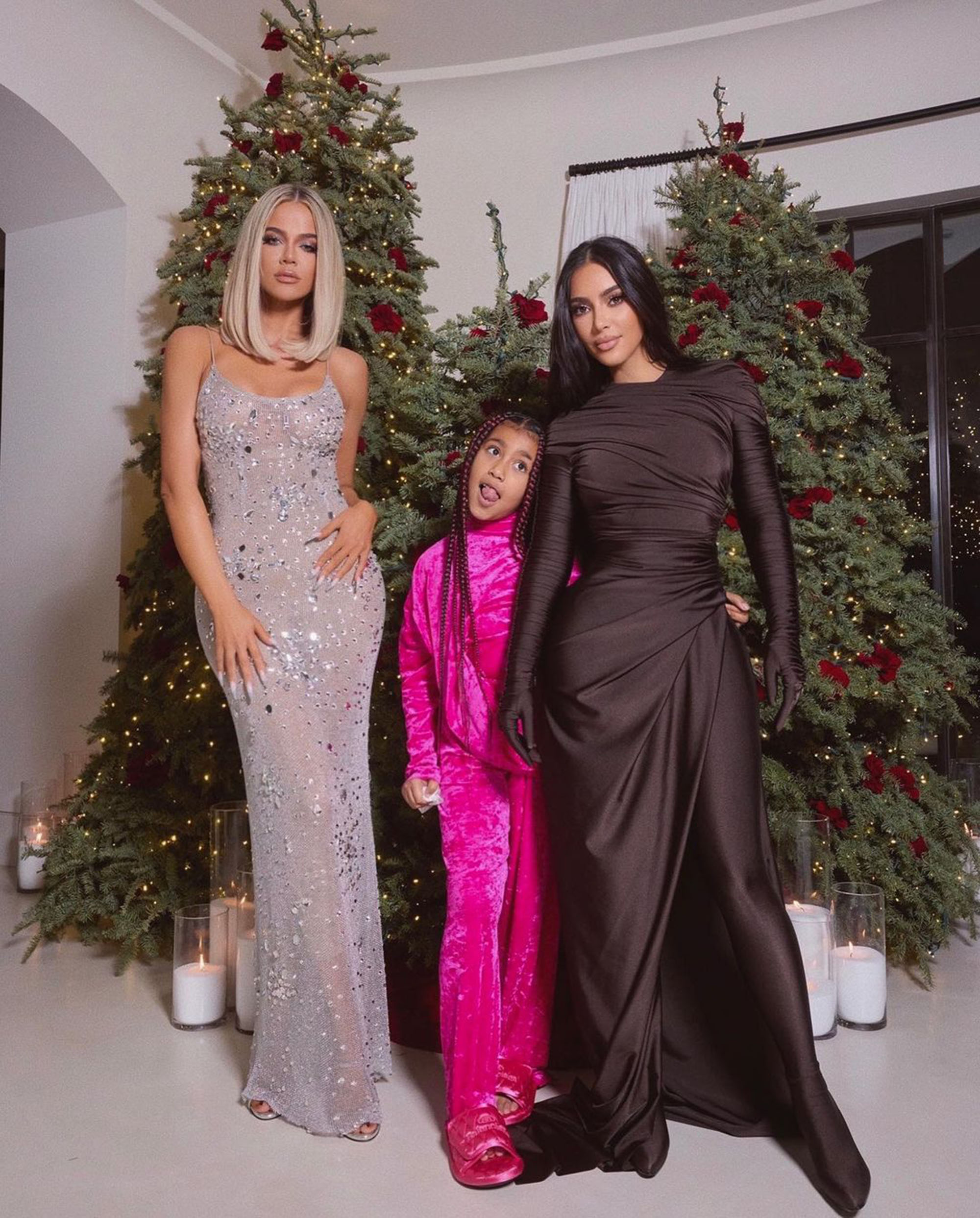 Khloé Kardashian, North West, and Kim Kardashian pose in front of Christmas trees.