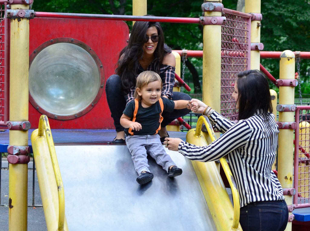 Kourtney Kardashian pushes Mason Disick down a slide. 