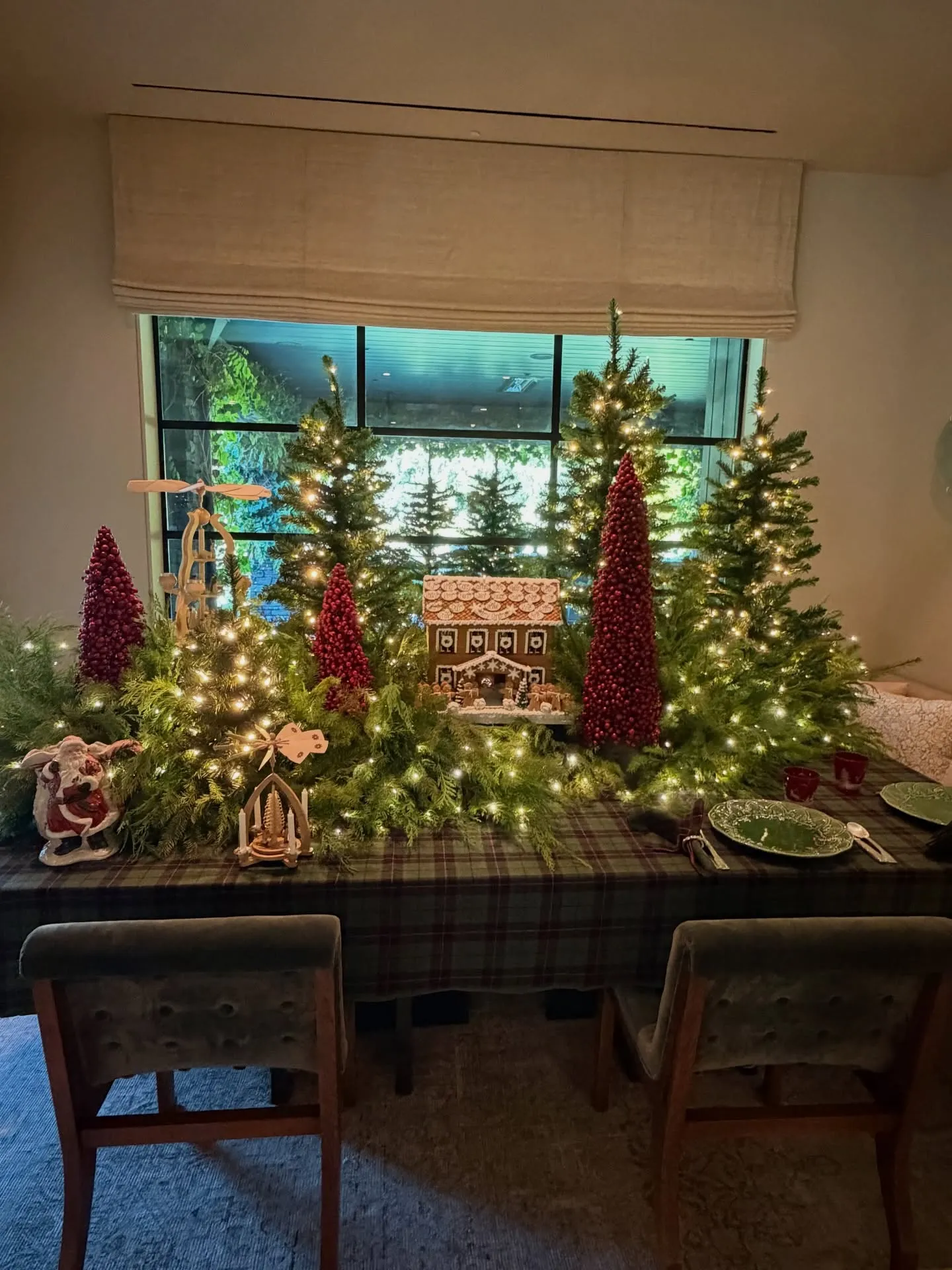 A gingerbread house on an elaborately set table with Christmas decorations.