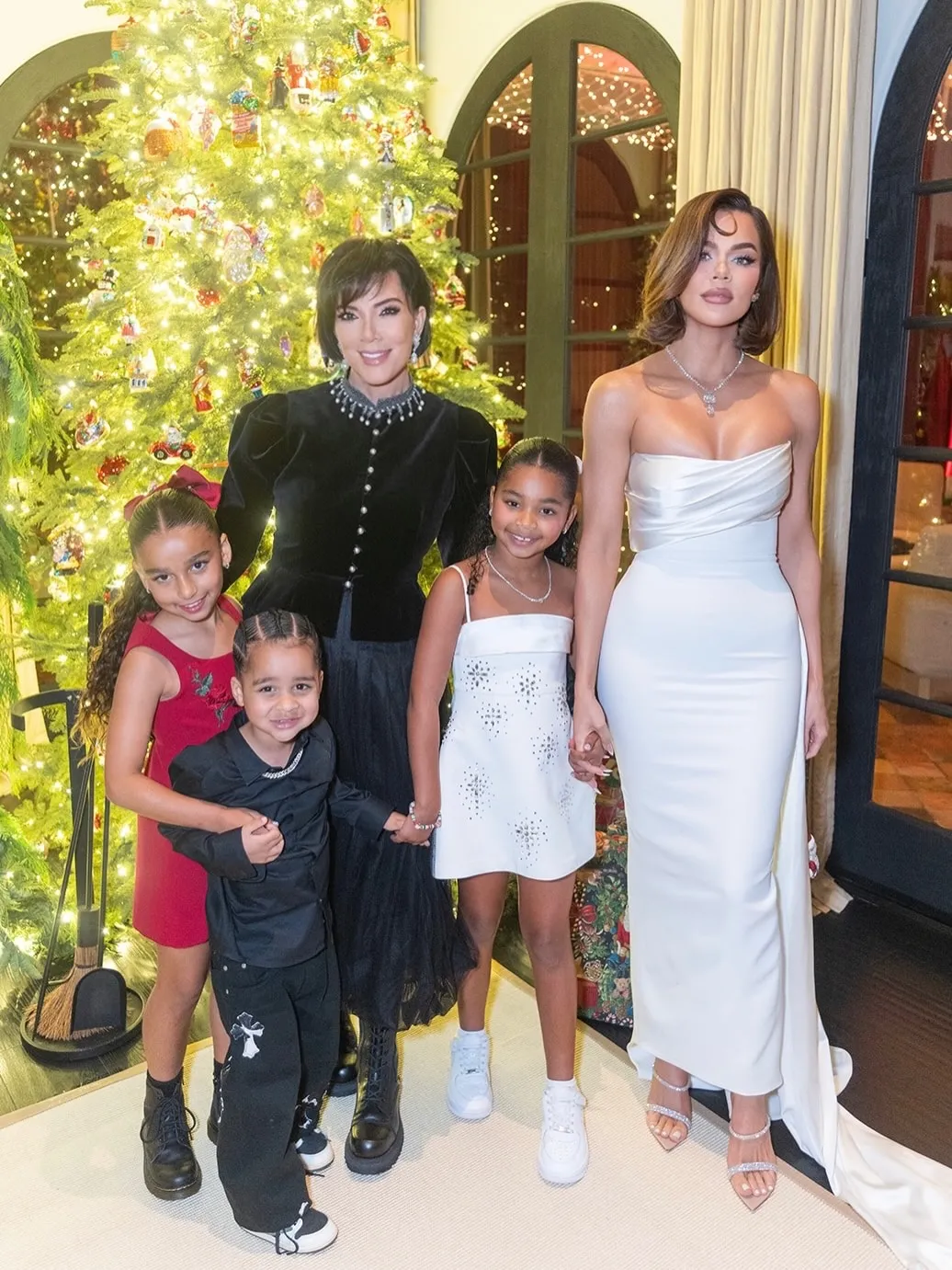 Kris Jenner with her daughter Khloé, and grandchildren True and Tatum, in front of a Christmas tree.