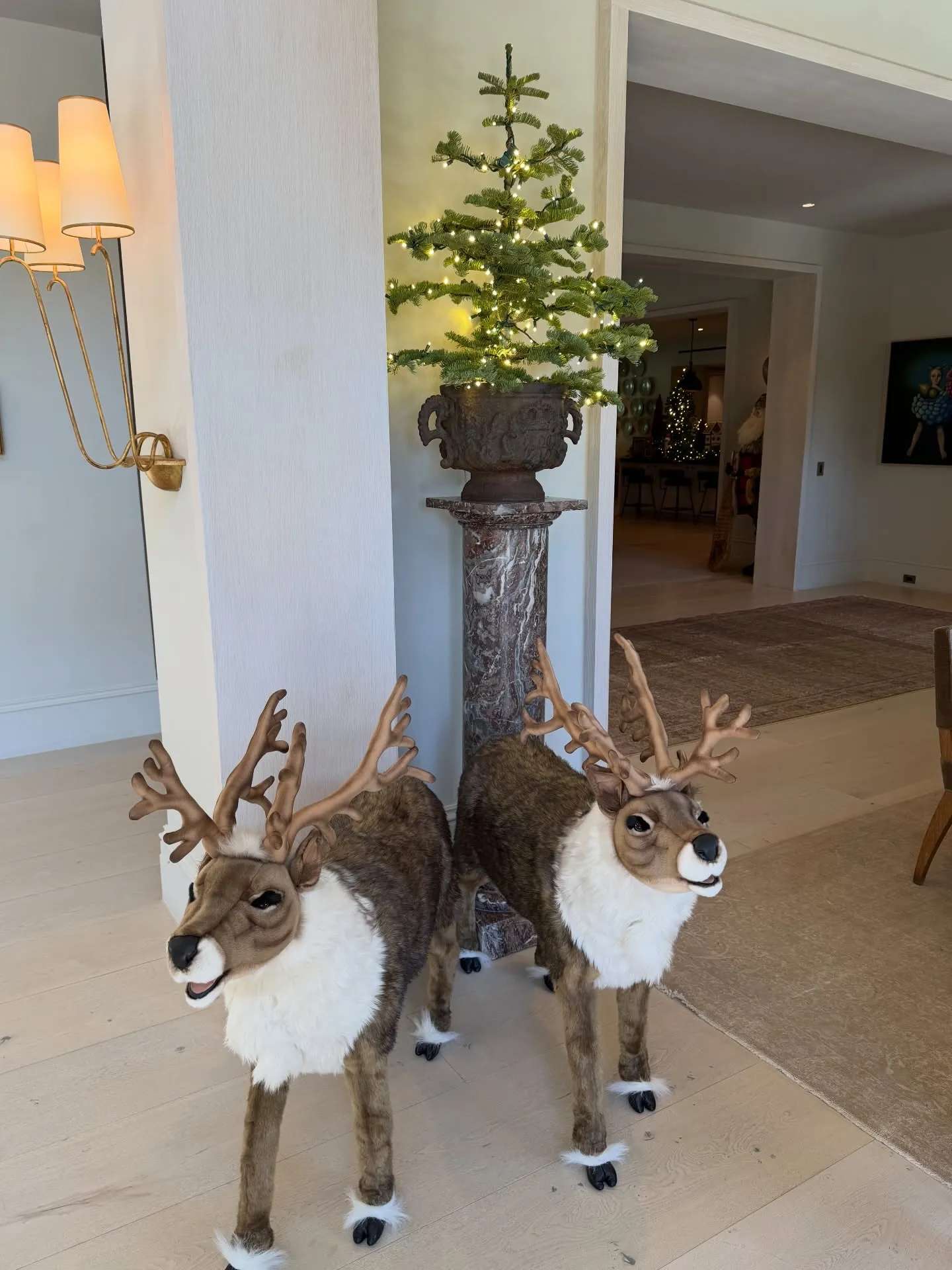 Two stuffed reindeer next to a decorated Christmas tree.