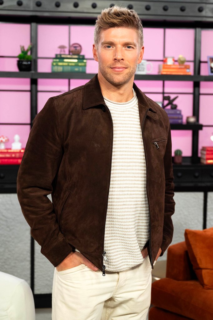 Kyle Cooke from Summer House wearing a brown jacket, striped shirt, and white pants.