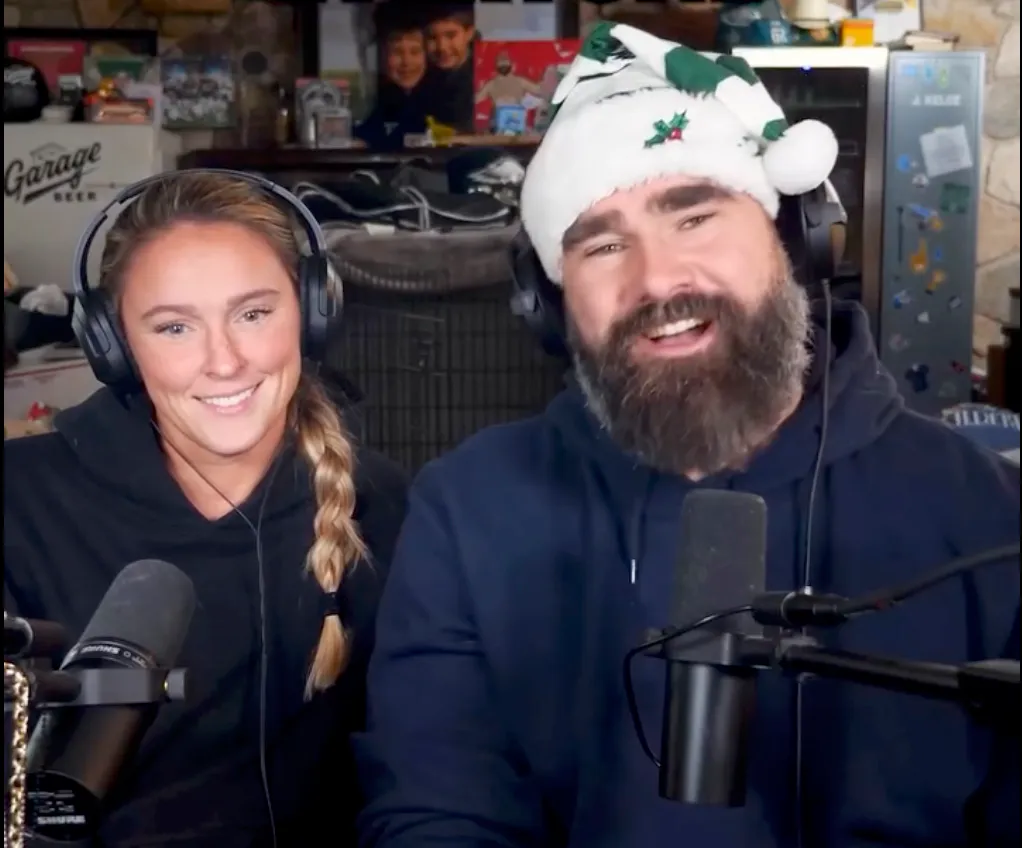 Kylie Kelce and Travis Kelce's brother, Jason, recording a podcast, with Jason wearing a festive hat.