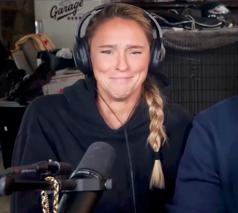 Kylie Kelce, wearing headphones, making a crying face while recording a podcast.
