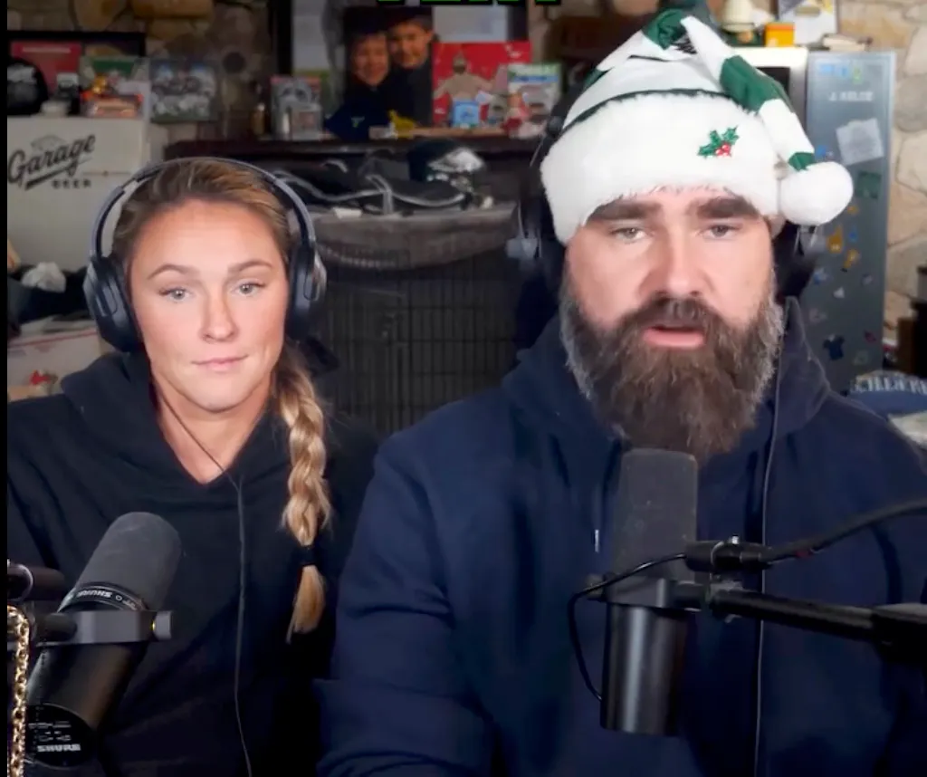 Kylie and Jason Kelce recording their podcast, with Jason wearing a festive hat.