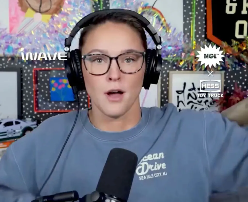 Kylie Kelce speaking into a microphone while wearing headphones and glasses.