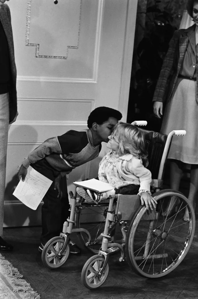Gary Coleman as Arnold Jackson kissing Melanie Watson as Kathy Gordon, who is in a wheelchair.