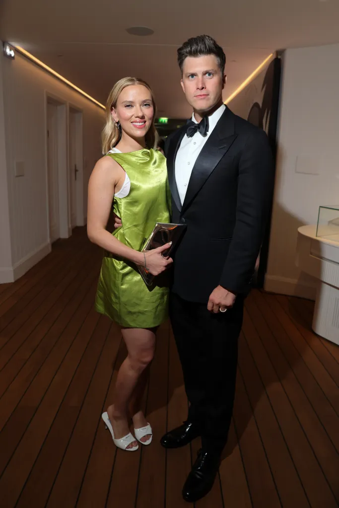 Scarlett Johansson in a bright green dress and Colin Jost in a tuxedo pose together.