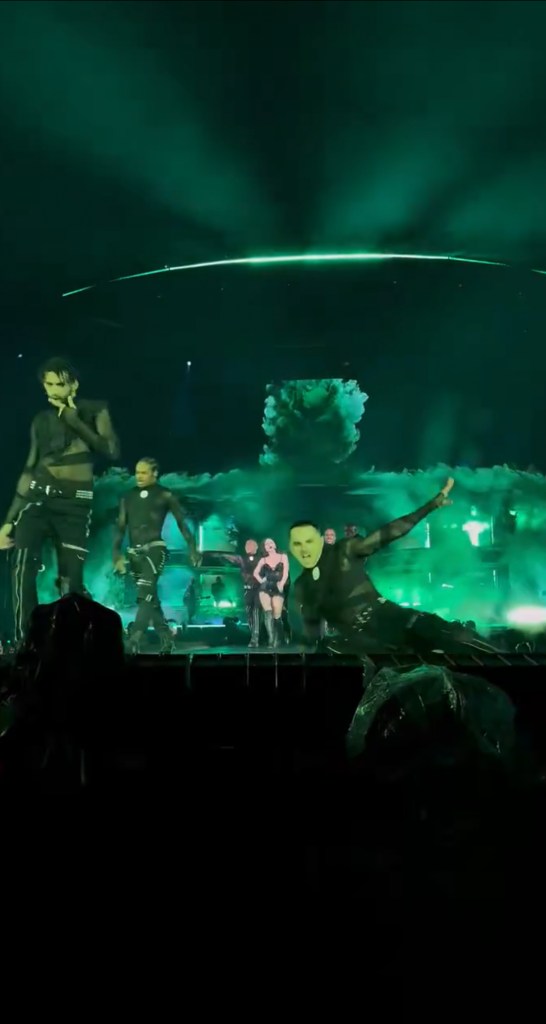 A male dancer in an all-black outfit falls off stage during a Lady Gaga concert.